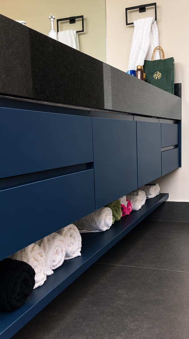 Gabinete azul sob bancada escura com nicho aberto para toalhas